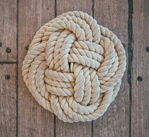 A symmetrical knot with thick rope lying on weathered wood.