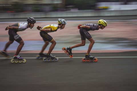 Three roller bladers in racing gear competing, with a blurred background.